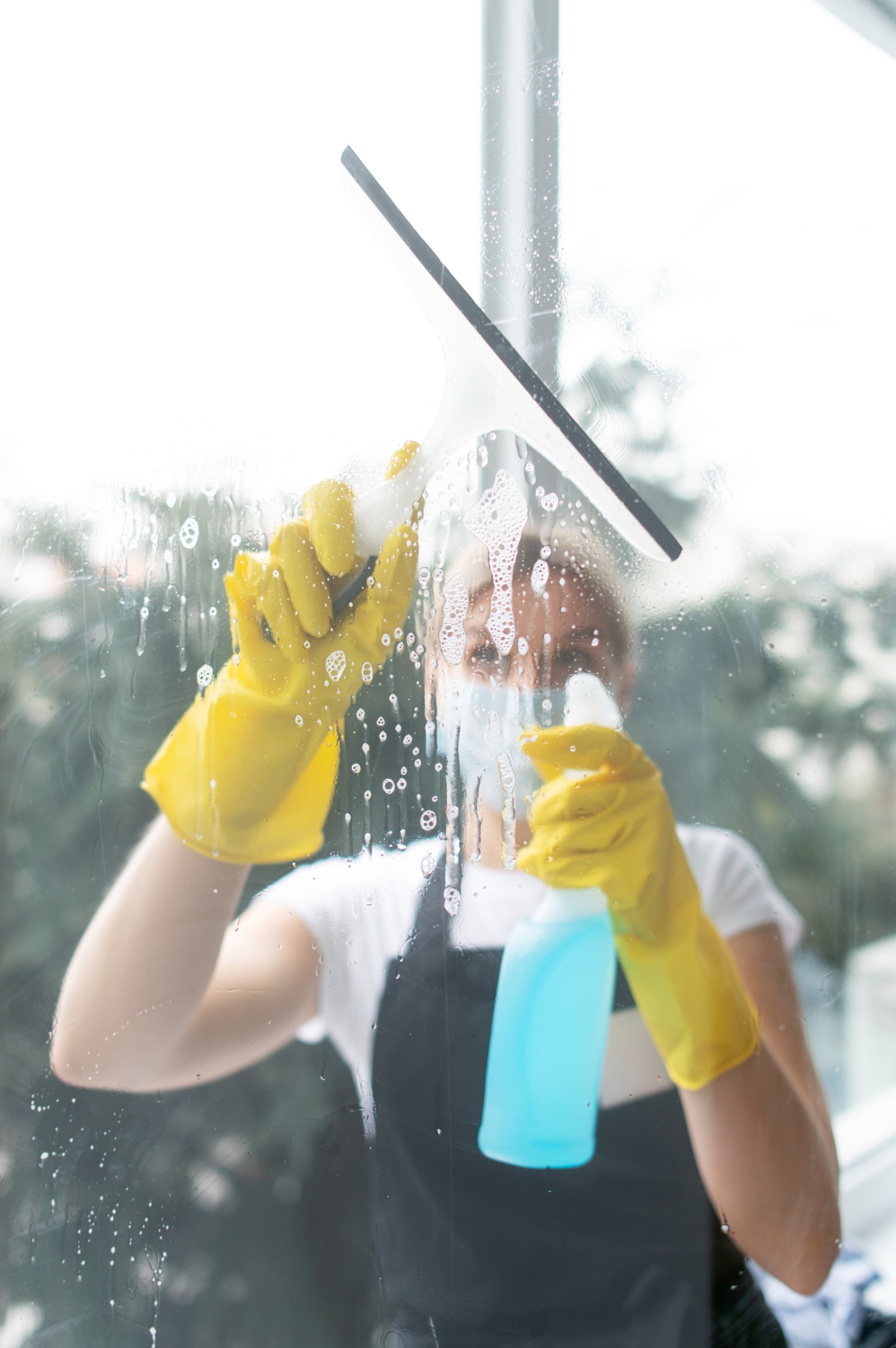Blick durch das Fenster auf eine Frau, die es putzt