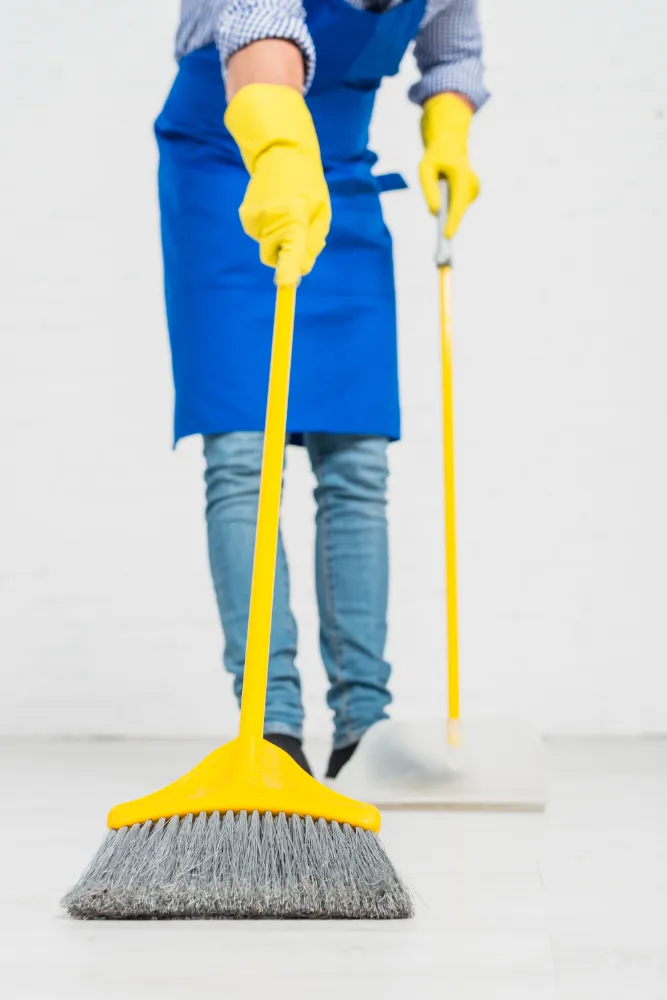 Eine Person in einer blauen Schürze wischt den Boden
